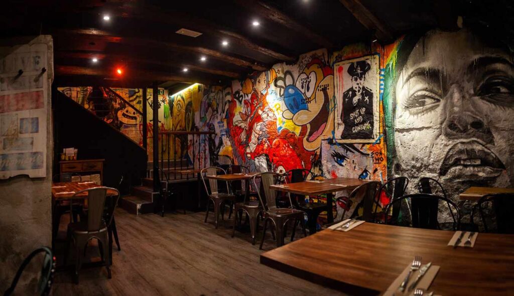 Interior moderno del restaurante Garua Bar en San Sebastián, con decoración de graffitis, iluminación cálida y ambiente acogedor