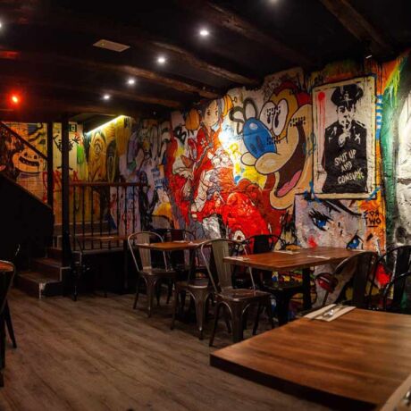 Interior moderno del restaurante Garua Bar en San Sebastián, con decoración de graffitis, iluminación cálida y ambiente acogedor