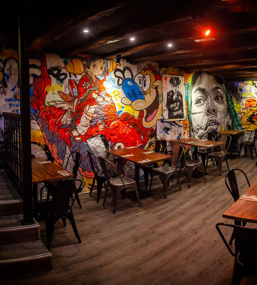 Interior moderno del restaurante Garua Bar en San Sebastián, con decoración de graffitis, iluminación cálida y ambiente acogedor