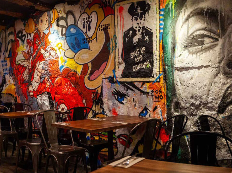 Interior moderno del restaurante Garua Bar en San Sebastián, con decoración de graffitis, iluminación cálida y ambiente acogedor