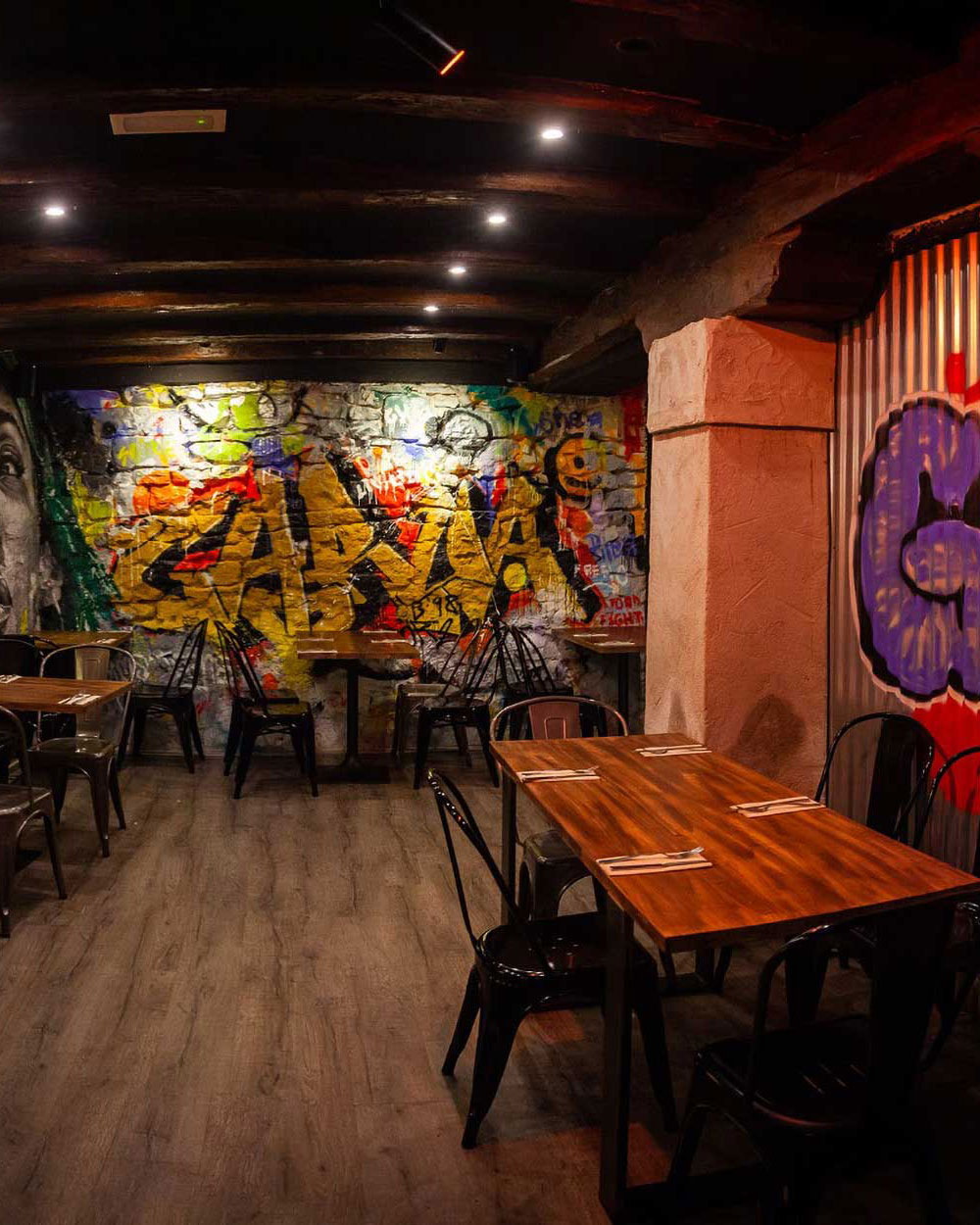 Interior moderno del restaurante Garua Bar en San Sebastián, con decoración de graffitis, iluminación cálida y ambiente acogedor