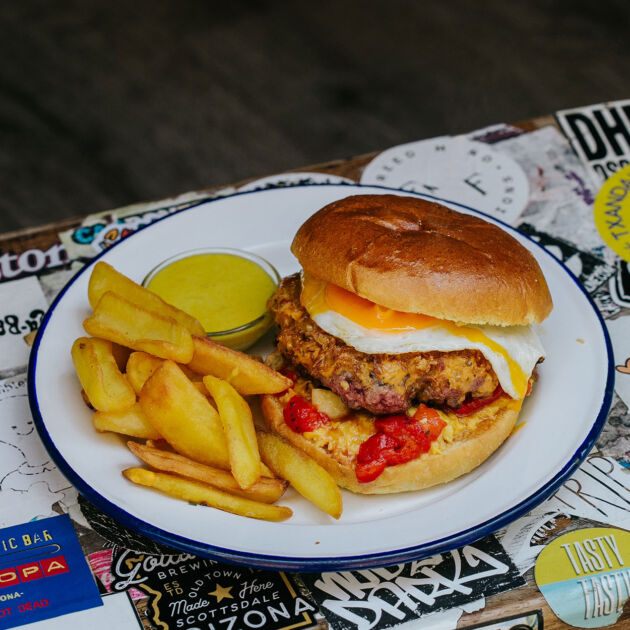 Hamburguesa Argentina Garúa con 180 g de carne de txuleta jugosa, cebolla frita, crema de maíz, chimichurri, huevo a la plancha, pimiento asado y patatas, en Garúa Bar de Donostia-San Sebastián