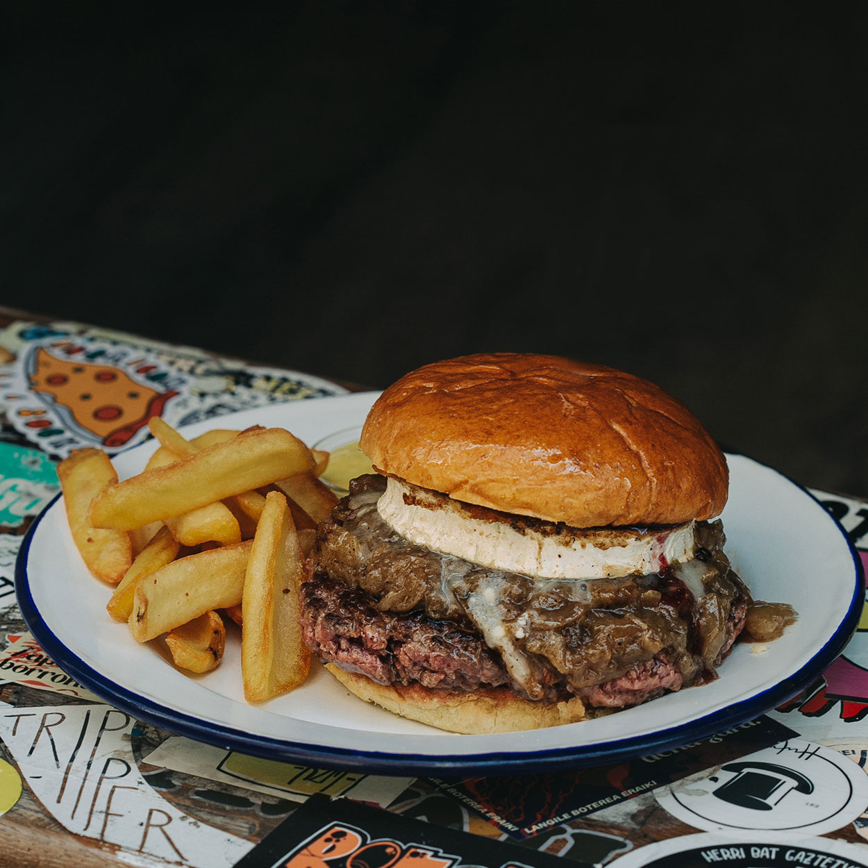 Hamburguesa de cabra Garúa con 180 g de carne de txuleta jugosa, queso de cabra cremoso fundido, cebolla pochada y confitura de frutos rojos, la mezcla perfecta de dulce y salado, en Garúa Bar de Donostia-San Sebastián