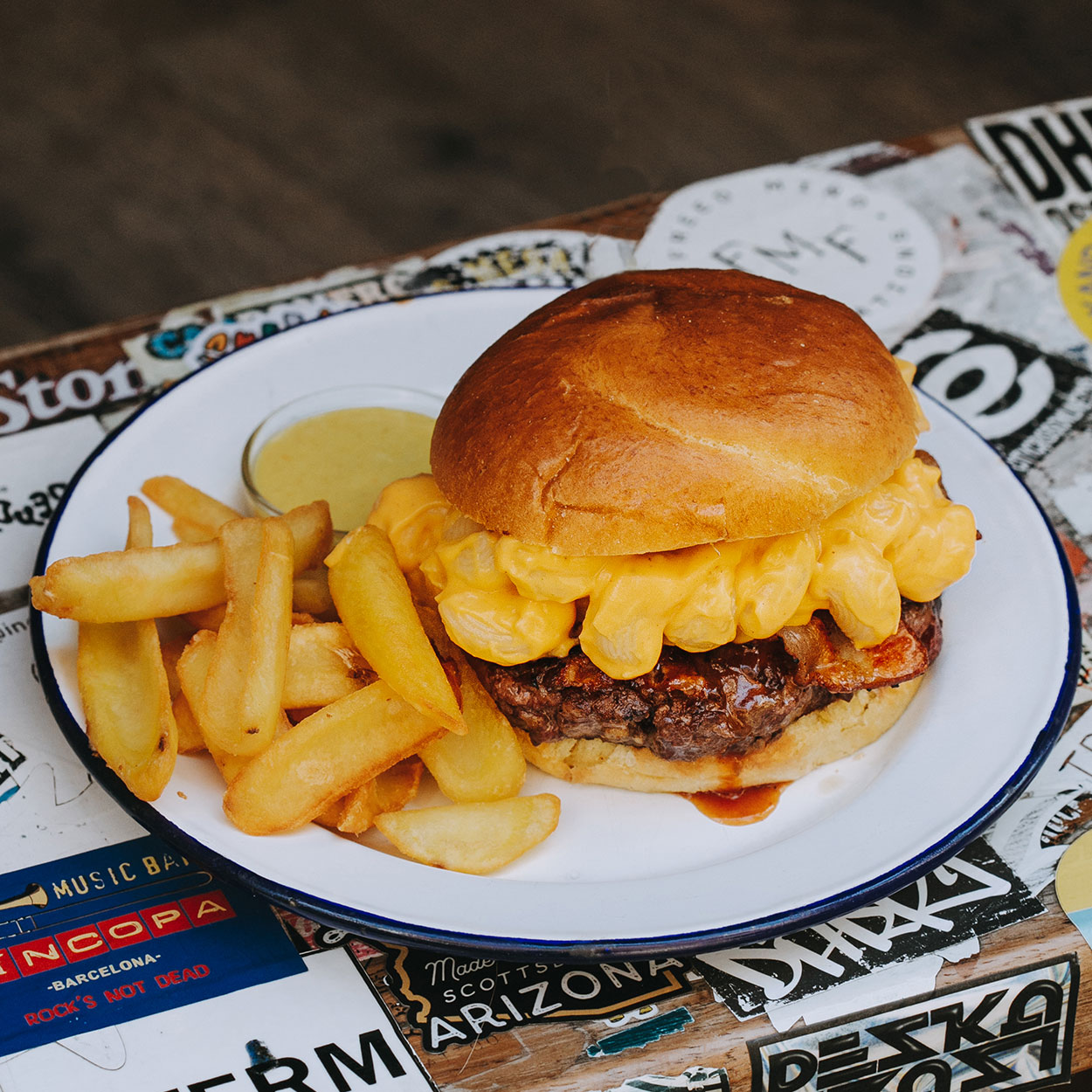 Hamburguesa Mac and Cheese Garua con 180 g de carne de chuleta jugosa, bacon crujiente, salsa barbacoa y macarrones con queso cremosos, acompañada de patatas doradas, en Garua Bar de Donostia-San Sebastián