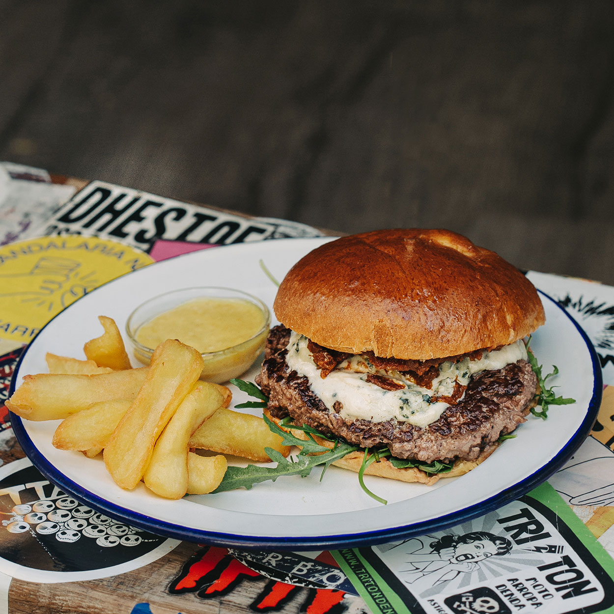 Hamburguesa Roquefort Garua con carne de chuleta, queso roquefort fundido, tomate seco y rúcula fresca acompañada de unas deliciosas patatas fritas en la hamburguesería Garua Bar de Donostia-San Sebastián