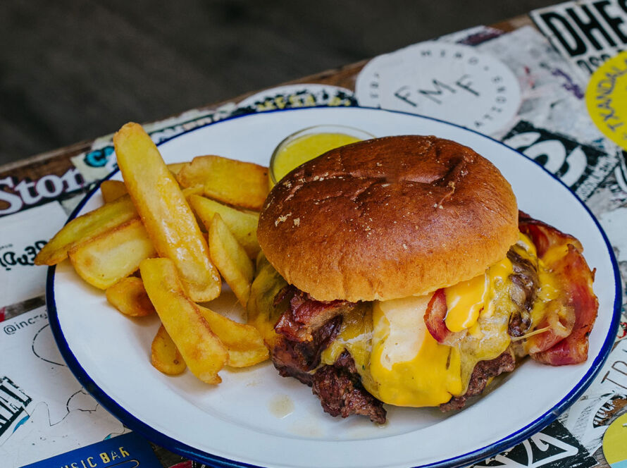 Hamburguesa Smash Garua con 180 g de carne de chuleta en dos discos crujientes, bacon crujiente, cebolla brunoise, queso cheddar fundido, salsa especial Garua y patatas doradas, en Garua Bar de Donostia-San Sebastián