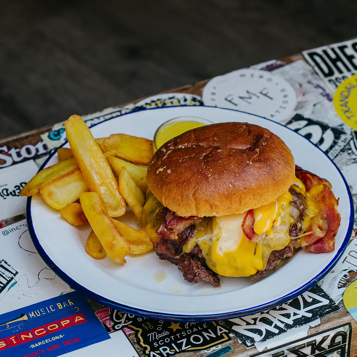 Hamburguesa Smash Garua con 180 g de carne de chuleta en dos discos crujientes, bacon crujiente, cebolla brunoise, queso cheddar fundido, salsa especial Garua y patatas doradas, en Garua Bar de Donostia-San Sebastián