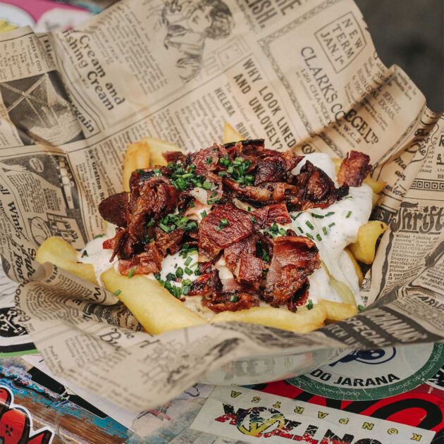 Patatas fritas con queso cheddar fundido y bacon crujiente en la hamburguesería Garua bar de Donostia-San Sebastián